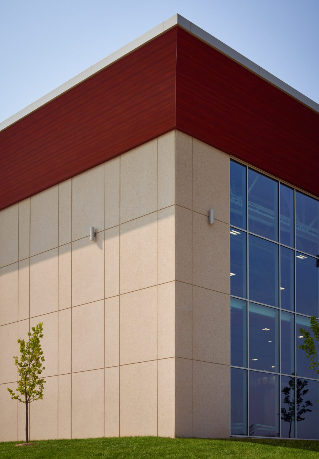 Corner of a white field house volume with a red cap and full-height glass at Rich Township High School