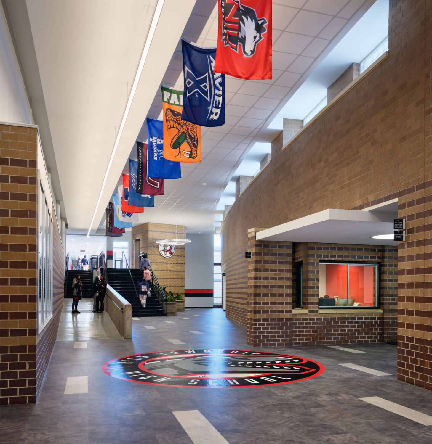 Main corridor with brick walls, a hanging banner display and the school seal set in the floor at Rich Township High School