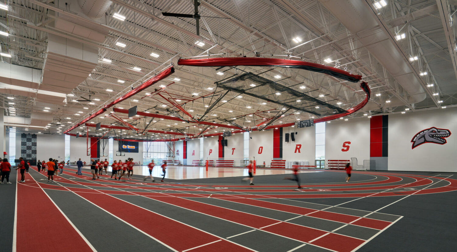 Field house with a red running track, curved banners and a high white ceiling at Rich Township High School