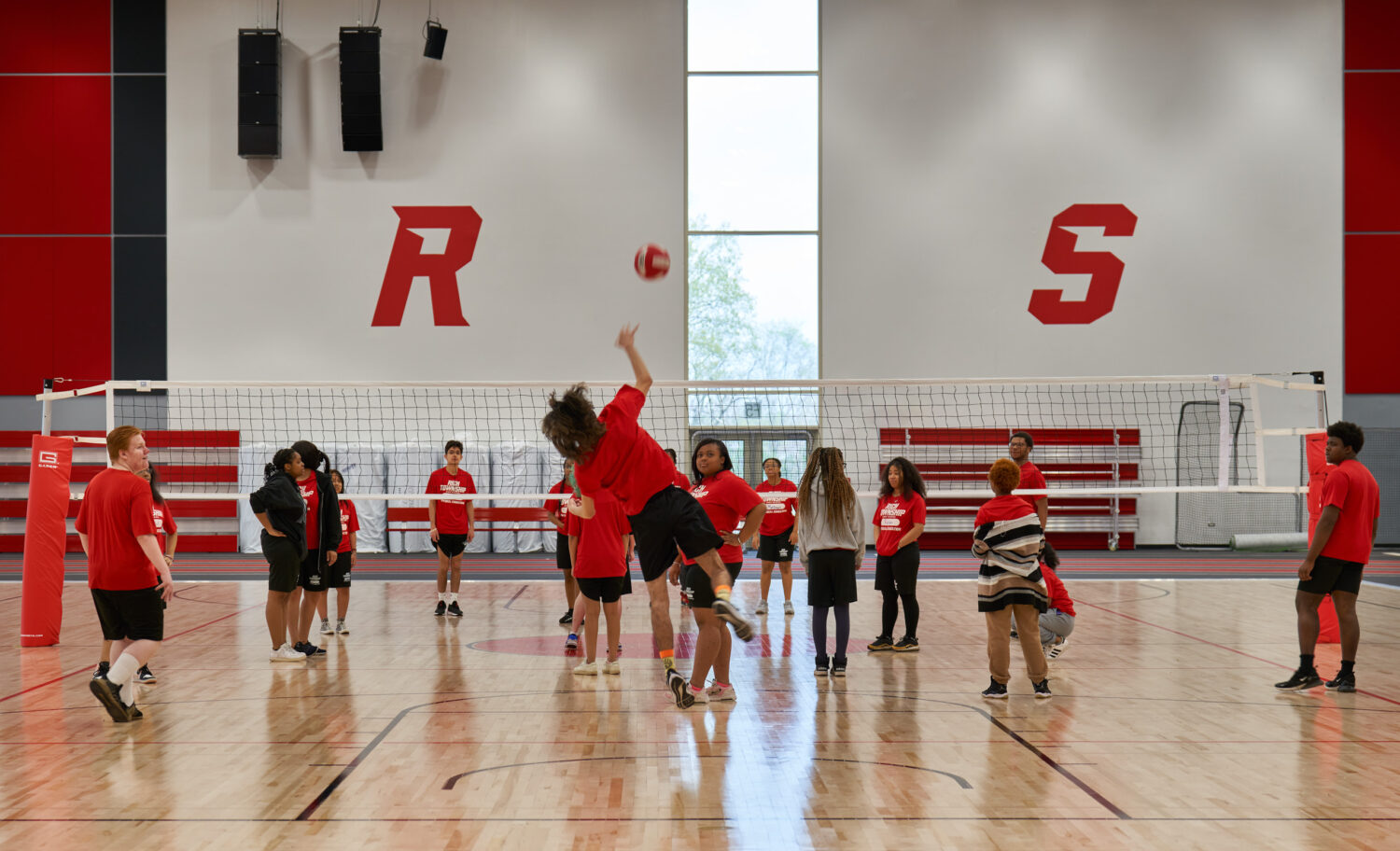 Students playing volleyball beneath red RS lettering in the gymnasium at Rich Township High School