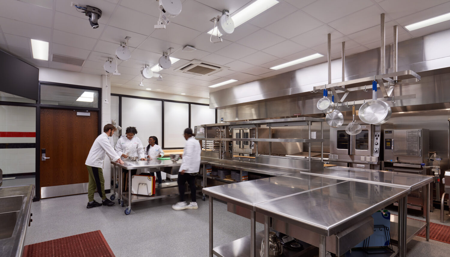 Culinary lab with stainless steel prep tables and students working with an instructor at Rich Township High School