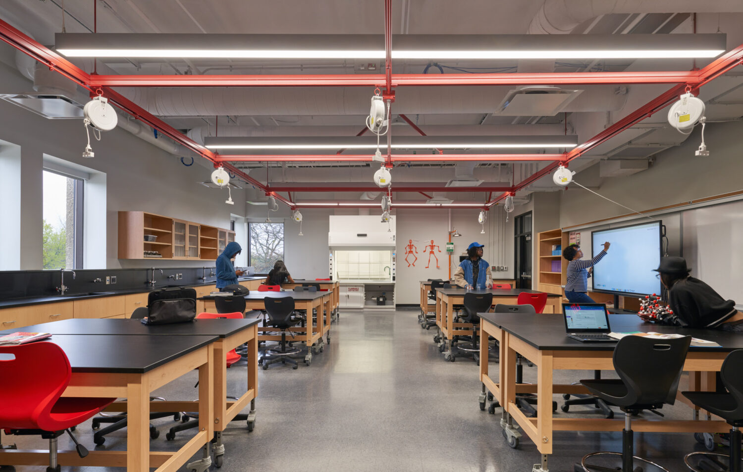Science classroom with black lab benches, red stools and exposed red ceiling ductwork at Rich Township High School