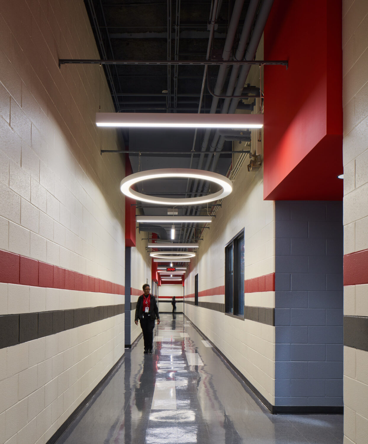 Long corridor with red and gray stripes and a ring-shaped light fixture at Rich Township High School