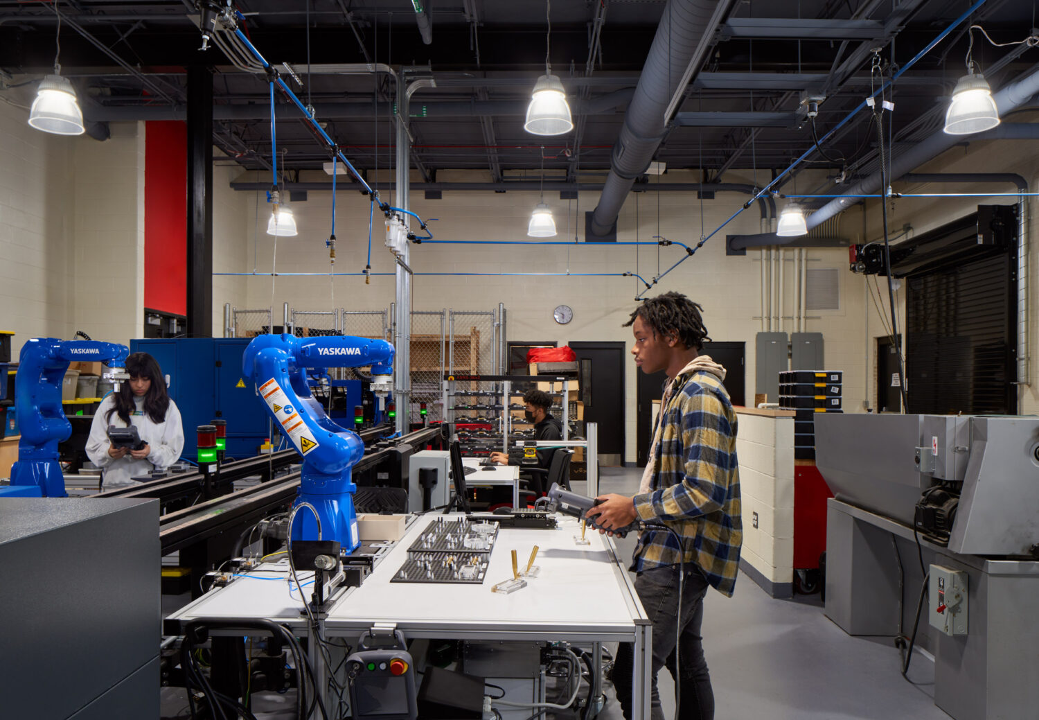 Students programming blue robotic arms in the engineering and robotics lab at Rich Township High School