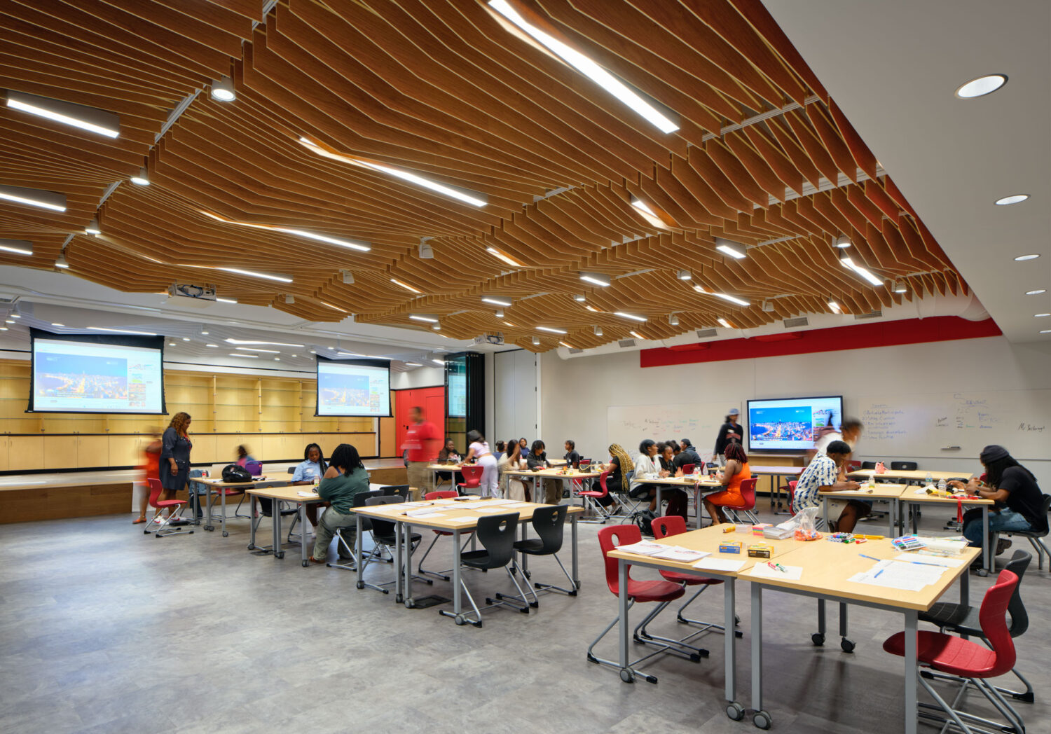 Cafeteria with a slatted wood ceiling, red tables and students eating lunch at Rich Township High School