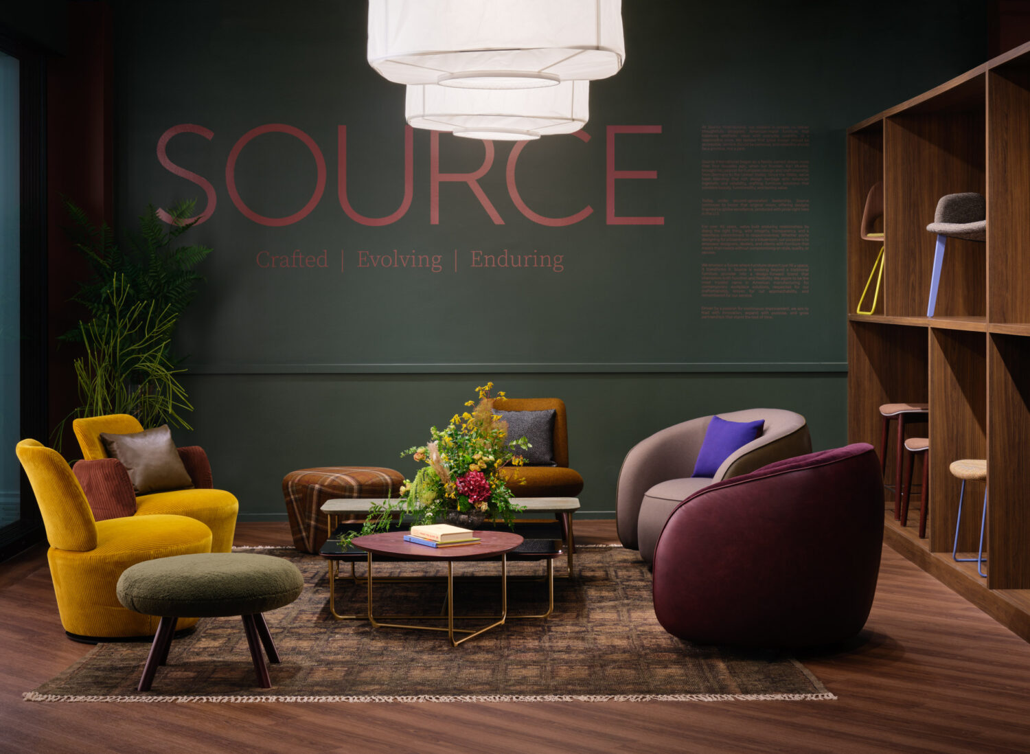 Mustard and plum lounge seating under paper lanterns before a dark green Source wall
