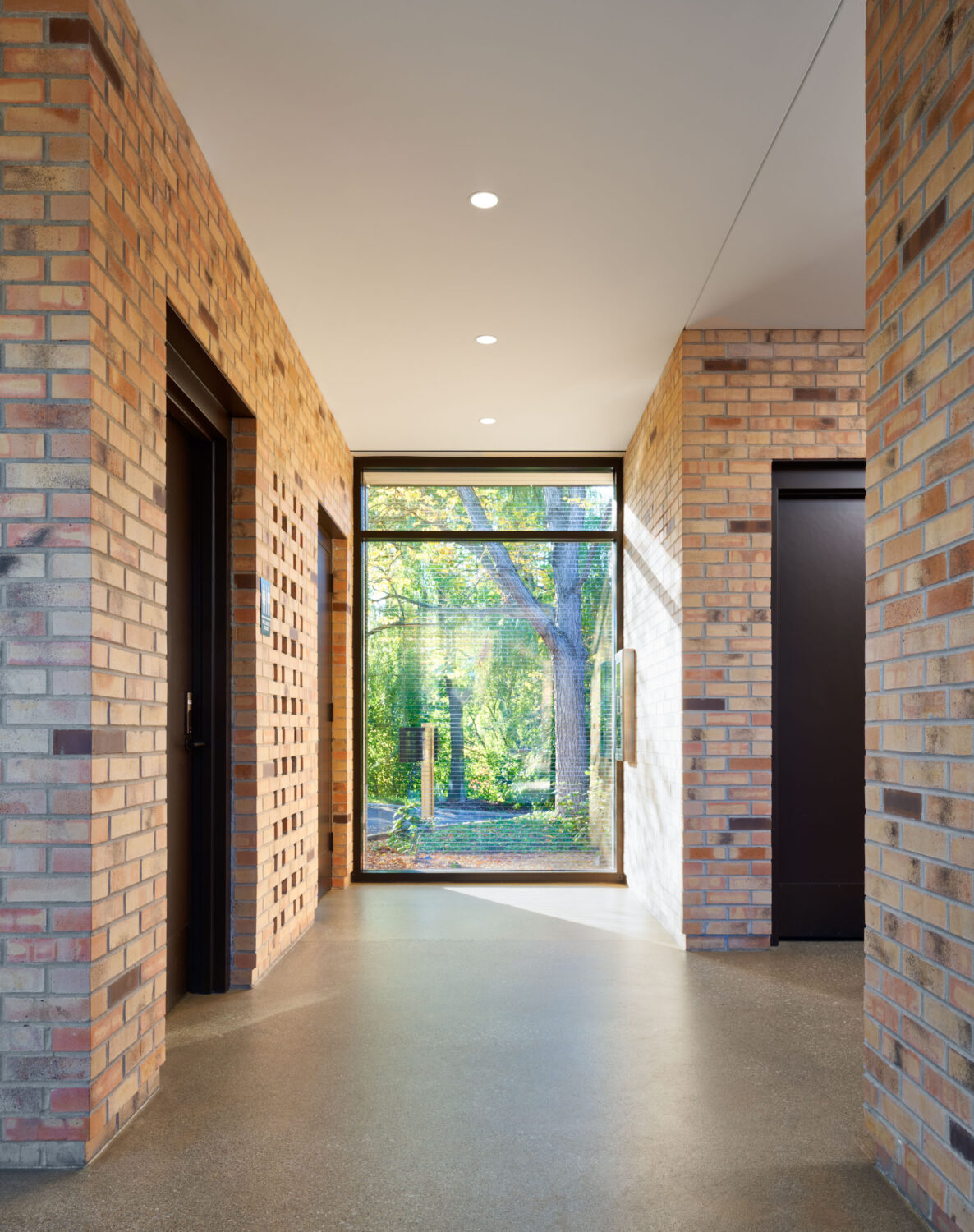 Brick corridor in a Chicago Botanic Garden pavilion ending in a full-height window onto the woods