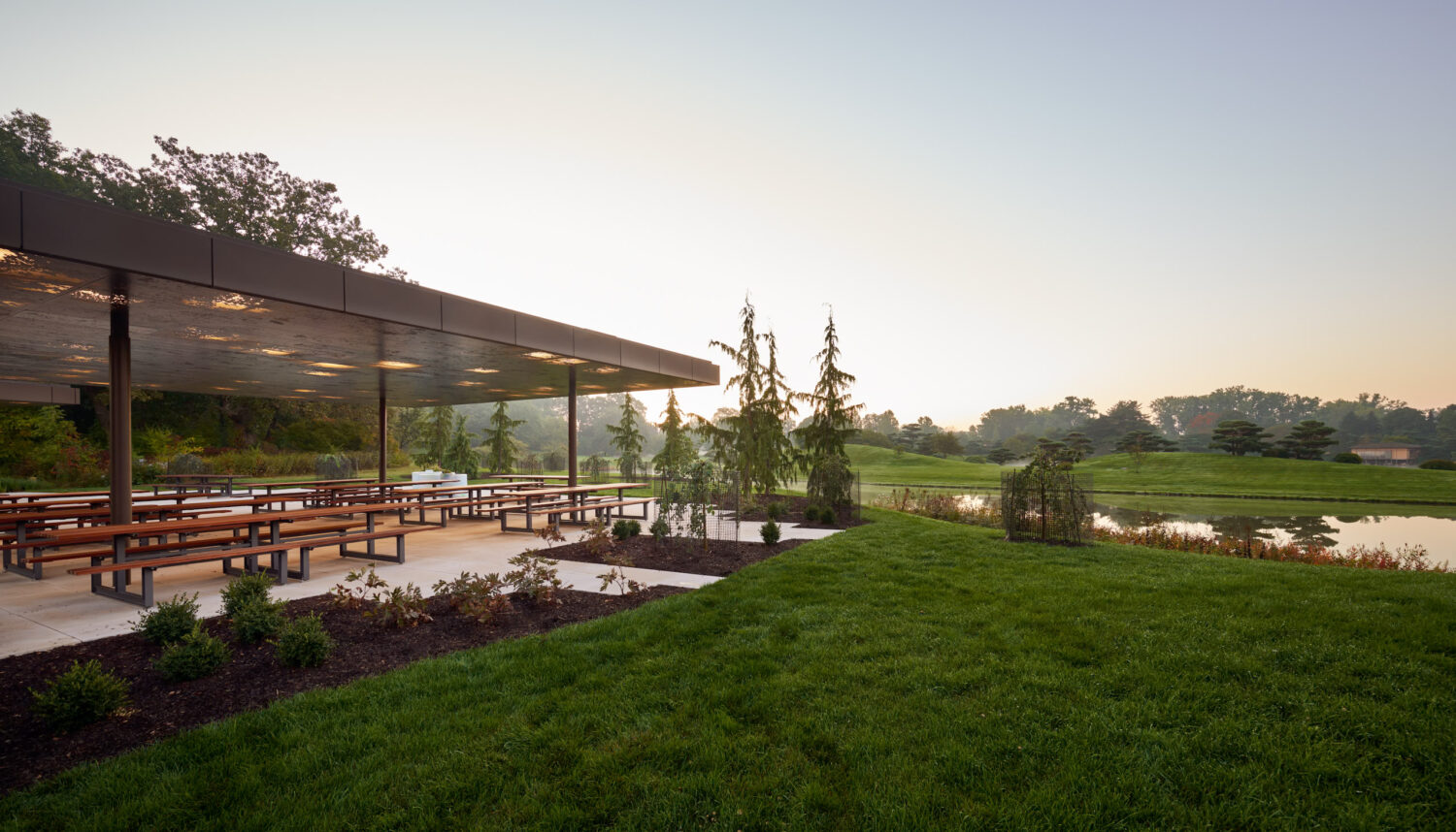 Picnic Glade pavilion at the Chicago Botanic Garden at dawn, picnic tables beside a lawn and lake