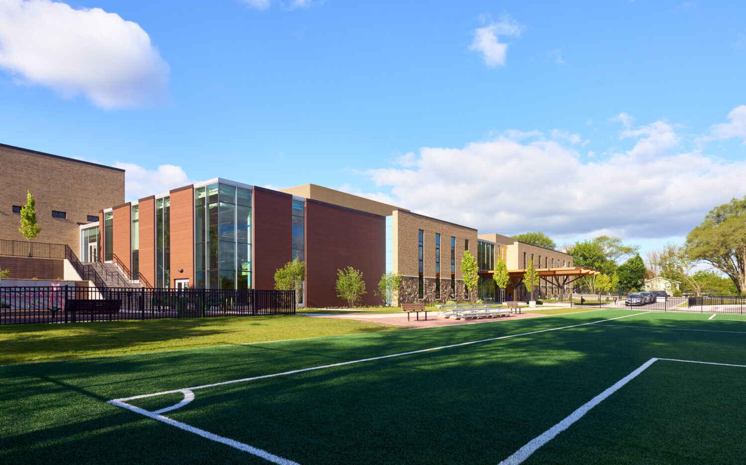 Long brick and glass elevation of the Kindergarten Center at Churchill Elementary seen across the turf playing field