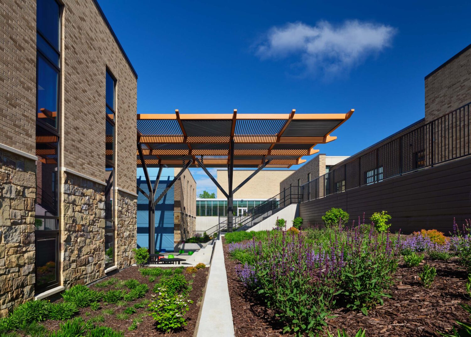 Reading garden with flowering plantings and a narrow path leading to the canopy at the Kindergarten Center at Churchill Elementary